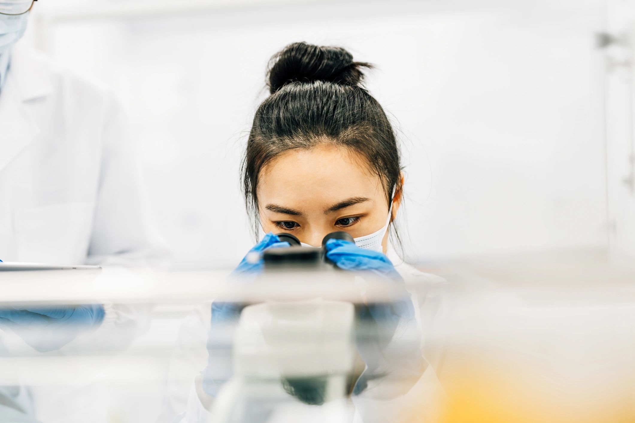 Lab technician performing failure analysis using a microscope