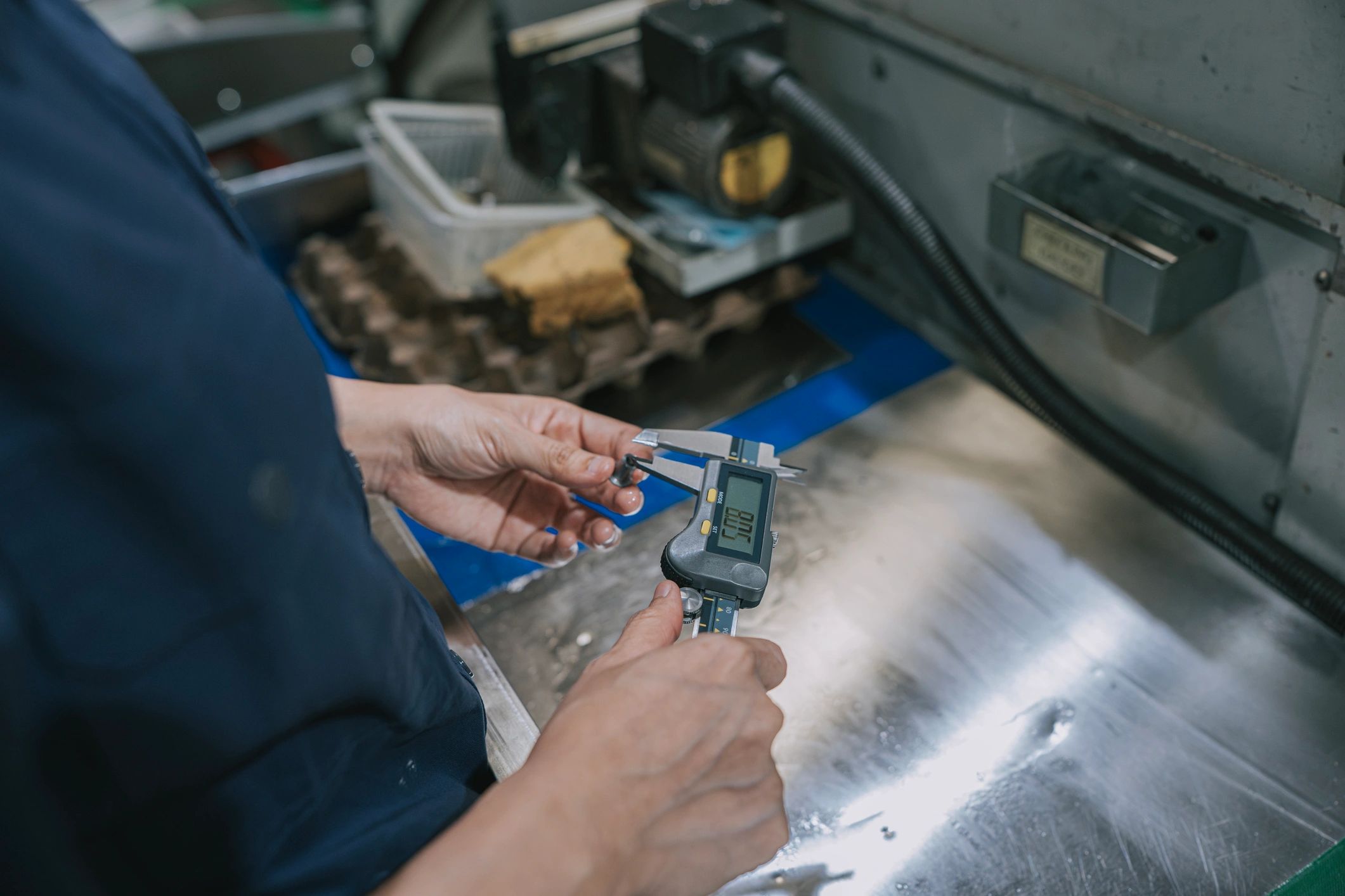 Technician measuring a machined part with a digital caliper